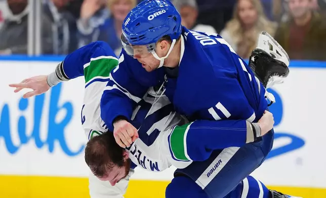Toronto Maple Leafs' Max Domi (11) and Vancouver Canucks' Marcus Pettersson, bottom, fight during second-period NHL hockey game action in Toronto, Saturday, Jan. 10, 2026. (Frank Gunn/The Canadian Press via AP)