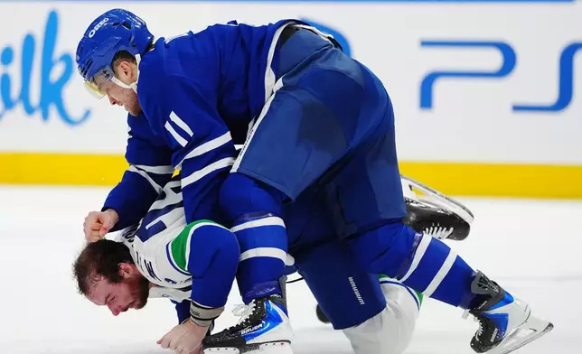 Toronto Maple Leafs' Max Domi (11) and Vancouver Canucks' Marcus Pettersson, bottom, fight during second-period NHL hockey game action in Toronto, Saturday, Jan. 10, 2026. (Frank Gunn/The Canadian Press via AP)