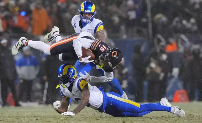 Chicago Bears wide receiver Rome Odunze (15) goes airborne after taking a hit from Los Angeles Rams safety Kam Curl, bottom, as linebacker Nate Landman, back, looks on during the first half of an NFL football divisional playoff game Sunday, Jan. 18, 2026, in Chicago. (AP Photo/Nam Y. Huh)