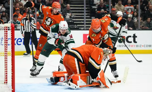 Minnesota Wild center Joel Eriksson Ek (14) tries to get the puck past Anaheim Ducks goaltender Lukas Dostal (1) and defenseman Radko Gudas (7) during the second period of an NHL hockey game Friday, Jan. 2, 2026, in Anaheim, Calif. (AP Photo/William Liang)