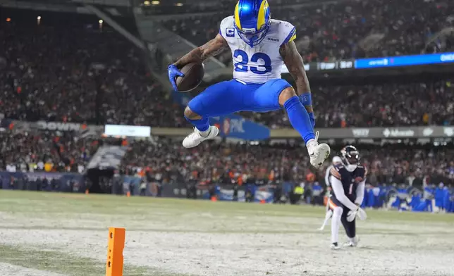 Los Angeles Rams running back Kyren Williams, front, scores a touchdown after evading a tackle by Chicago Bears cornerback Jaylon Johnson during the second half of an NFL football divisional playoff game Sunday, Jan. 18, 2026, in Chicago. (AP Photo/Jeff Roberson)