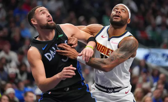Dallas Mavericks guard Klay Thompson, left, and Denver Nuggets guard Bruce Brown scramble on a free throw by the Nuggets during the first half of an NBA basketball game Wednesday, Jan. 14, 2026, in Dallas. (AP Photo/Julio Cortez)