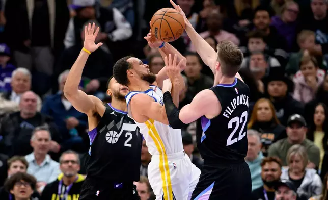 Golden State Warriors guard Stephen Curry, center, has the ball knocked away by Utah Jazz forward Kyle Filipowski, right, as he was driving to the basket during the first half of an NBA basketball game, Wednesday, Jan. 28, 2026, in Salt Lake City. (AP Photo/Tyler Tate)