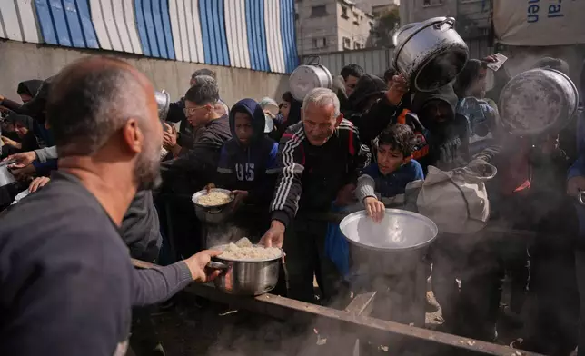 Palestinians receive donated food at a community kitchen in Nuseirat, in central Gaza Strip, Saturday, Jan. 24, 2026. (AP Photo/Abdel Kareem Hana)