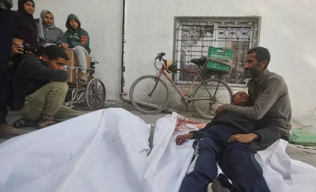 EDS NOTE: GRAPHIC CONTENT - Yusuf Zawara mourns over the body of his son, Mohammad Zawara, 15, who was killed along with his cousin Sulaiman Zawara, 13, left, in an Israeli strike, according to health officials, at Shifa Hospital, Gaza City, Saturday, Jan. 24, 2026. (AP Photo/Yousef Al Zanoun)