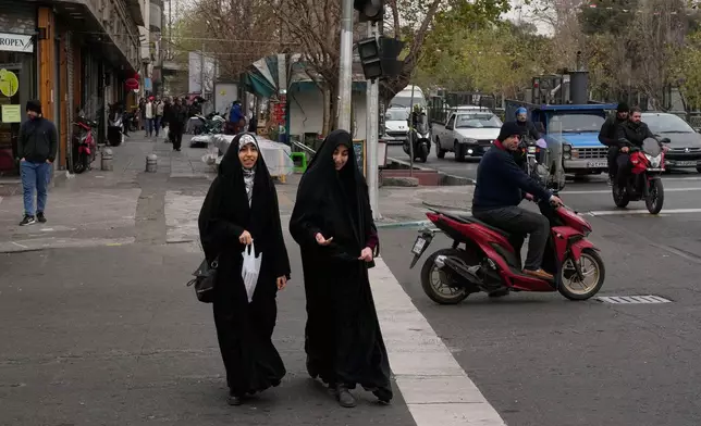 Women cross an intersection in downtown Tehran, Iran, Thursday, Jan. 15, 2026. (AP Photo/Vahid Salemi)