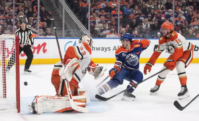 Anaheim Ducks' goalie Ville Husso (33) is scored on as Edmonton Oilers' Matt Savoie (22) and Ducks' Drew Helleson (14) watch the puck go in the net during the second period of an NHL hockey game in Edmonton on Monday, Jan. 26, 2026. (Jason Franson/The Canadian Press via AP)