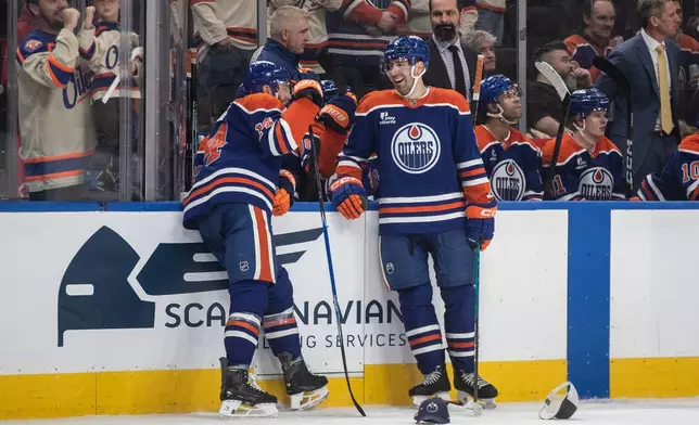 Edmonton Oilers' Mattias Ekholm (14) and Evan Bouchard, right, laugh after Ekholm scored a hat trick during third-period NHL hockey game action against the Anaheim Ducks in Edmonton, Alberta, Monday, Jan. 26, 2026. (Jason Franson/The Canadian Press via AP)