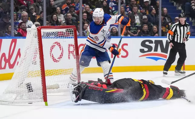 Edmonton Oilers' Jack Roslovic (28) scores against Vancouver Canucks goalie Nikita Tolopilo, bottom right, during the second period of an NHL hockey game in Vancouver, British Columbia, Saturday, Jan. 17, 2026. (Darryl Dyck/The Canadian Press via AP)