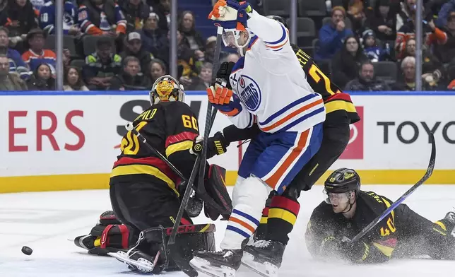 Edmonton Oilers' Zach Hyman, center, celebrates a goal by teammate Vasily Podkolzin, not seen, against Vancouver Canucks goalie Nikita Tolopilo (60) as Elias Pettersson (40) watches during the second period of an NHL hockey game, in Vancouver, British Columbia, on Saturday, Jan. 17, 2026. (Darryl Dyck/The Canadian Press via AP)