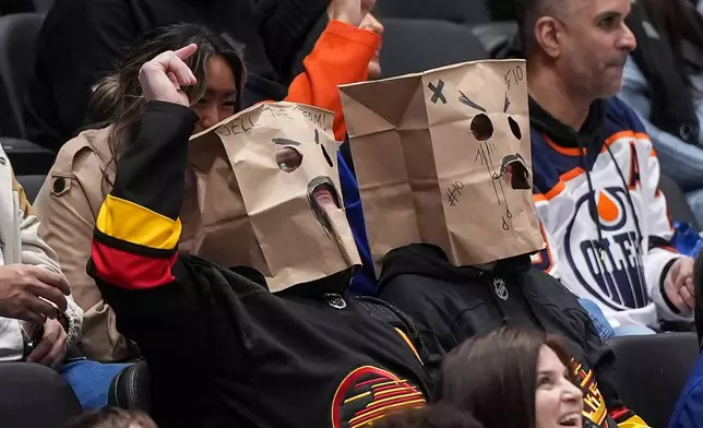 Vancouver Canucks fans wear paper bags on their heads during the third period of a 6-0 loss to the Edmonton Oilers during an NHL hockey game, in Vancouver, on Saturday, Jan. 17, 2026. (Darryl Dyck/The Canadian Press via AP)