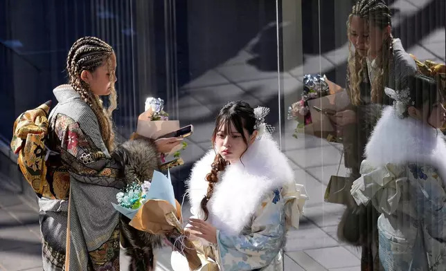 Young adults pause after marking the Coming-of-Age Day, a centuries-old tradition and national holiday marking the milestone from childhood to adulthood, Monday, Jan. 12, 2026, in Yokohama near Tokyo. (AP Photo/Eugene Hoshiko)
