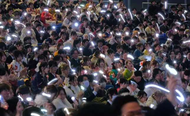 Young adults hold up their lighted mobile phones to celebrate the Coming-of-Age Day, a centuries-old tradition and national holiday marking the milestone from childhood to adulthood, Monday, Jan. 12, 2026, in Yokohama near Tokyo. (AP Photo/Eugene Hoshiko)