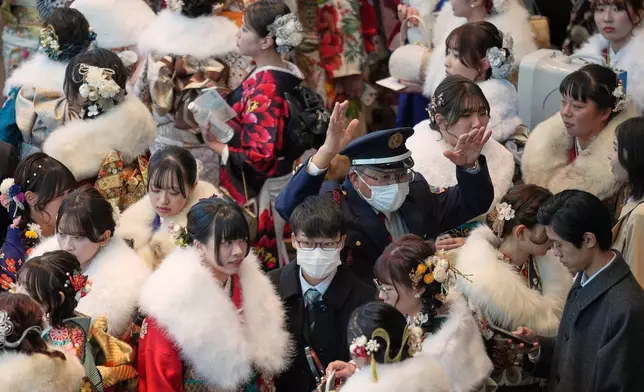A security person controls the flow of the young adults celebrate the Coming-of-Age Day, a centuries-old tradition and national holiday marking the milestone from childhood to adulthood, Monday, Jan. 12, 2026, in Yokohama near Tokyo. (AP Photo/Eugene Hoshiko)