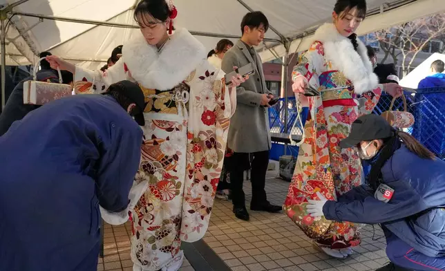 Kimono-clad women are checked at a security checkpoint as they arrive to celebrate the Coming-of-Age Day, a centuries-old tradition and national holiday marking the milestone from childhood to adulthood, Monday, Jan. 12, 2026, in Yokohama near Tokyo. (AP Photo/Eugene Hoshiko)