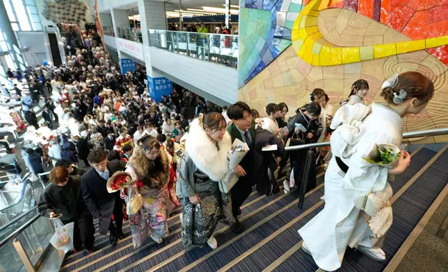 Young adults arrive at a venue to celebrate the Coming-of-Age Day, a centuries-old tradition and national holiday marking the milestone from childhood to adulthood, Monday, Jan. 12, 2026, in Yokohama near Tokyo. (AP Photo/Eugene Hoshiko)
