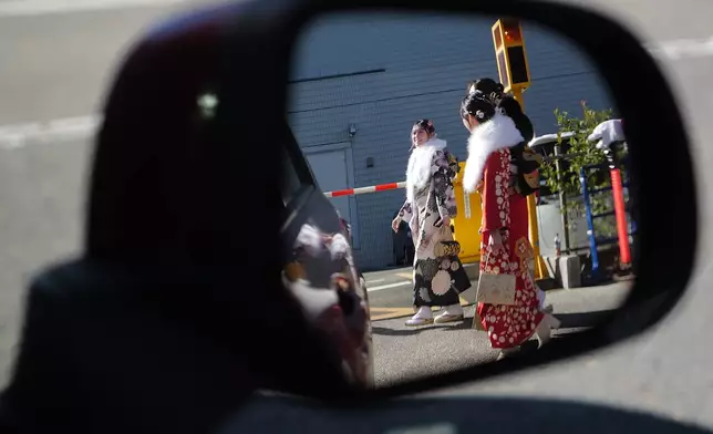 Young adults with kimono walk to celebrate the Coming-of-Age Day, a centuries-old tradition and national holiday marking the milestone from childhood to adulthood, Monday, Jan. 12, 2026, in Yokohama near Tokyo. (AP Photo/Eugene Hoshiko)