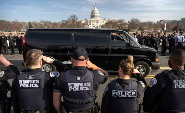Metropolitan Police Department officers salute as a van carrying the body of MPD officer Terry Bennett, who died on Wednesday, weeks after being struck by a motorist, is driven past the Capitol, Thursday, Jan. 8, 2026, in Washington. (AP Photo/Mark Schiefelbein)