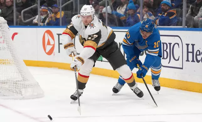 Vegas Golden Knights' Ben Hutton (17) passes as St. Louis Blues' Brayden Schenn (10) watches during the second period of an NHL hockey game Friday, Jan. 2, 2026, in St. Louis. (AP Photo/Jeff Roberson)