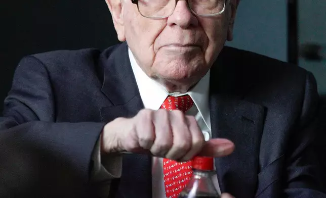 FILE - Warren Buffett, chairman and CEO of Berkshire Hathaway, opens a bottle of Cherry Coke during a game of bridge outside Berkshire-owned Borsheims jewelry store in Omaha, Neb., Sunday, May 6, 2018. (AP Photo/Nati Harnik, File)