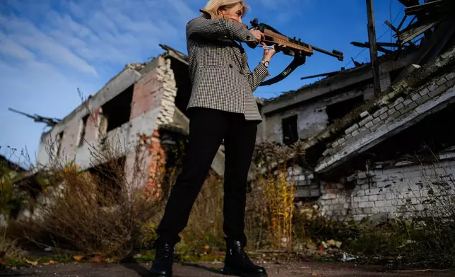 Retired biathlete and deputy Minister of Youth and Sports of Ukraine Nina Lemesh poses for photos outside the destroyed ski base in Chernihiv, Ukraine, Thursday, Oct. 30, 2025. (AP Photo/Julia Demaree Nikhinson)
