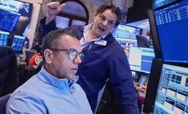 Traders Robert Finnerty Jr., foreground, and Michael Milano work on the floor of the New York Stock Exchange, Monday, Jan. 26, 2026. (AP Photo/Richard Drew)