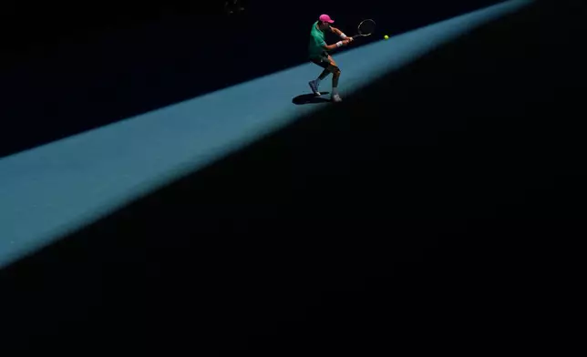 Raphael Collignon of Belgium plays a backhand return to Lorenzo Musetti of Italy during their first round match at the Australian Open tennis championship in Melbourne, Australia, Tuesday, Jan. 20, 2026. (AP Photo/Aaron Favila)