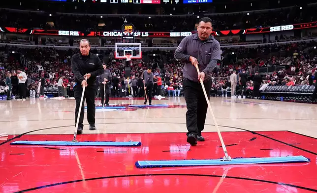 United Center employees try to dry the court before an NBA basketball game between the Miami Heat and the Chicago Bulls in Chicago, Thursday, Jan. 8, 2026. (AP Photo/Nam Y. Huh)