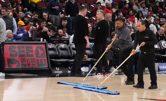United center employees clean the court during a delay before an NBA basketball game between the Chicago Bulls and the Miami Heat in Chicago, Thursday, Jan. 8, 2026. (AP Photo/Nam Y. Huh)