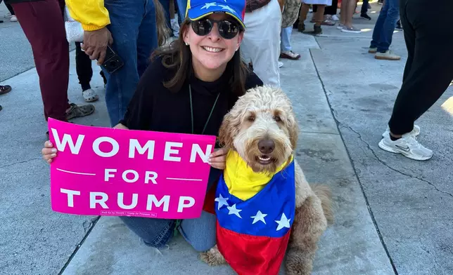 Alejandra Arrieta, 55, and her dog Bella pose for a photo outside of El Arepazo restaurant to celebrate the news of Venezuelan President Nicolás Maduro capture in Doral, Fla., on Saturday, Jan. 3, 2026. (AP Photo/Vanessa Alvarez)