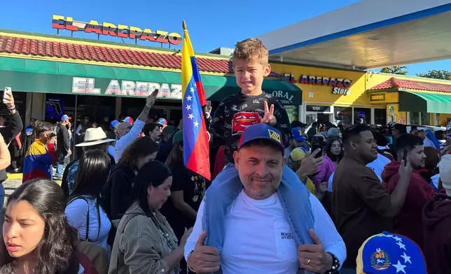 Lorenzo Coppola, 47, and his son Valentino join others to celebrate the news of Venezuelan President Nicolás Maduro capture in Doral, Fla., on Saturday, Jan. 3, 2026. (AP Photo/Vanessa Alvarez)