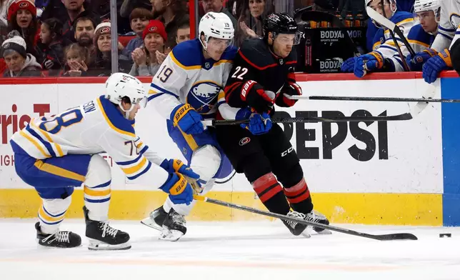 Carolina Hurricanes' Logan Stankoven (22) battles with Buffalo Sabres' Peyton Krebs (19) and Jacob Bryson (78) during the second period of an NHL hockey game in Raleigh, N.C., Monday, Jan. 19, 2026. (AP Photo/Karl DeBlaker)