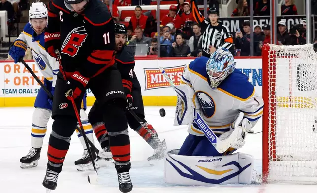Buffalo Sabres goaltender Ukko-Pekka Luukkonen (1) blocks a shot of the Carolina Hurricanes with Jordan Staal (11) and Jordan Martinook (48) nearby during the second period of an NHL hockey game in Raleigh, N.C., Monday, Jan. 19, 2026. (AP Photo/Karl DeBlaker)