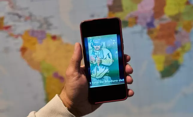 David Vallenilla holds a picture of deposed President Nicolas Maduro, blindfolded and handcuffed, during an interview with The Associated Press at his home in Madrid, Tuesday, Jan. 13, 2026. (AP Photo/Bernat Armangue)