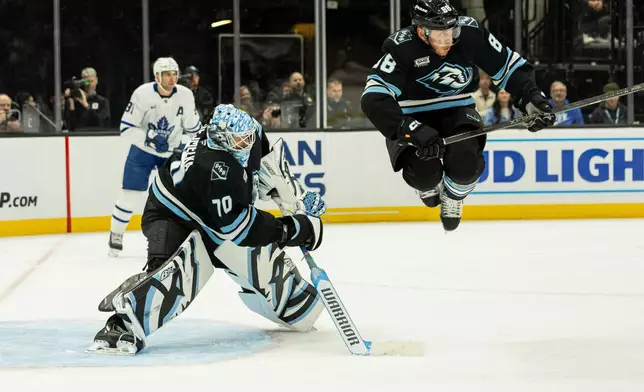 Utah Mammoth defenseman Nate Schmidt (88) jumps over Utah Mammoth goaltender Karel Vejmelka (70) hockey stick during the game against the Toronto Maple Leafs during the second period of an NHL hockey game Tuesday, Jan. 13, 2026, in Salt Lake City. (AP Photo/Melissa Majchrzak)