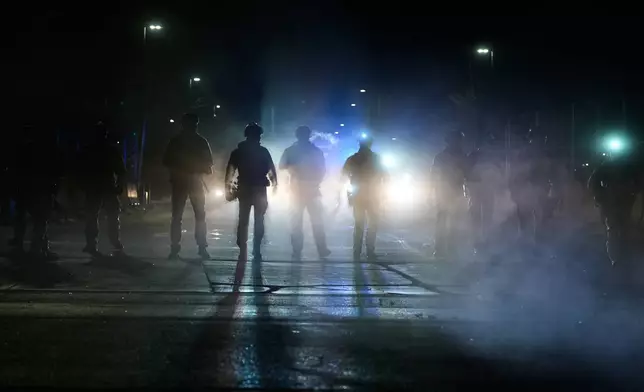 Federal immigration officers are seen outside Bishop Whipple Federal Building after tear gas was deployed Monday, Jan. 12, 2026, in Minneapolis. (AP Photo/Jen Golbeck)