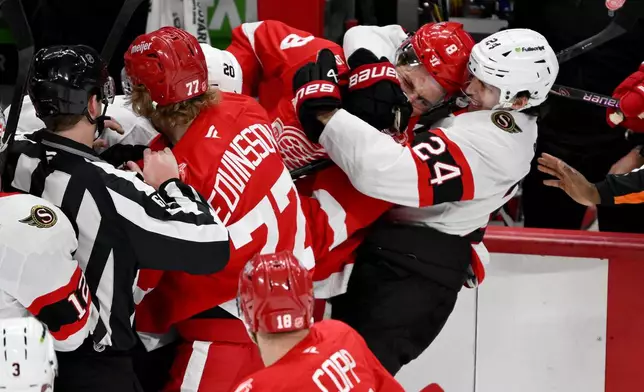 Ottawa Senators center Dylan Cozens (24) and Detroit Red Wings defenseman Ben Chiarot (8) fight in front of the team benches in the first period of an NHL hockey game, Sunday, Jan. 18, 2026, in Detroit. (AP Photo/Lon Horwedel)