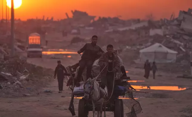 Palestinians walk through the ruins of destroyed buildings as the sun sets over Gaza City, Sunday, Jan. 4, 2026. (AP Photo/Jehad Alshrafi)