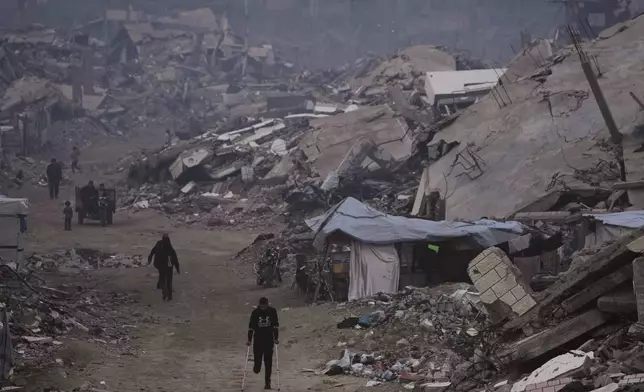 Palestinians walk through the ruins of destroyed buildings in Gaza City, Sunday, Jan. 4, 2026. (AP Photo/Jehad Alshrafi)