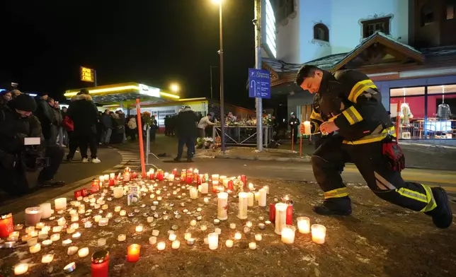 People lay candles and flowers near the Le Constellation bar, where a devastating fire left dead and injured during the New Year's celebrations in Crans-Montana, Swiss Alps, Switzerland, Thursday, Jan. 1, 2026. (AP Photo/ Antonio Calanni)