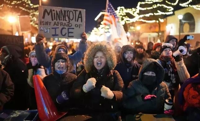Protesters chant and bang on trash cans as they stand behind a makeshift barricade during a protest in response to the death of 37-year-old Alex Pretti, who was fatally shot by a U.S. Border Patrol officer earlier in the day, Saturday, Jan. 24, 2026, in Minneapolis. (AP Photo/Adam Gray)