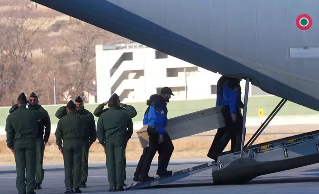 Police officers carry a coffin with a body of one of six Italians at the Military Airport in Sion, Swiss Alps, Switzerland, Monday, Jan. 5, 2026, following a devastating fire left dead and injured in a bar in Crans-Montana during the New Year's celebrations. (AP Photo/Antonio Calanni)