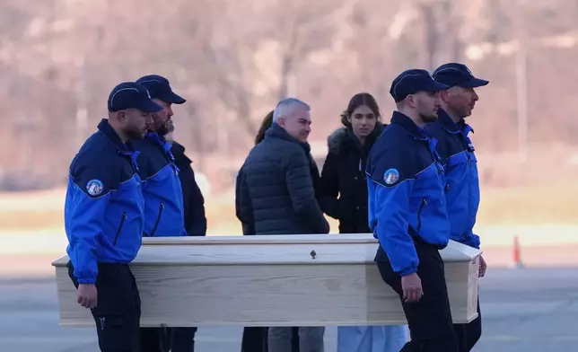 Police officers carry a coffin with a body of one of six Italians at the Military Airport in Sion, Swiss Alps, Switzerland, Monday, Jan. 5, 2026, following a devastating fire left dead and injured in a bar in Crans-Montana during the New Year's celebrations. (AP Photo/Antonio Calanni)