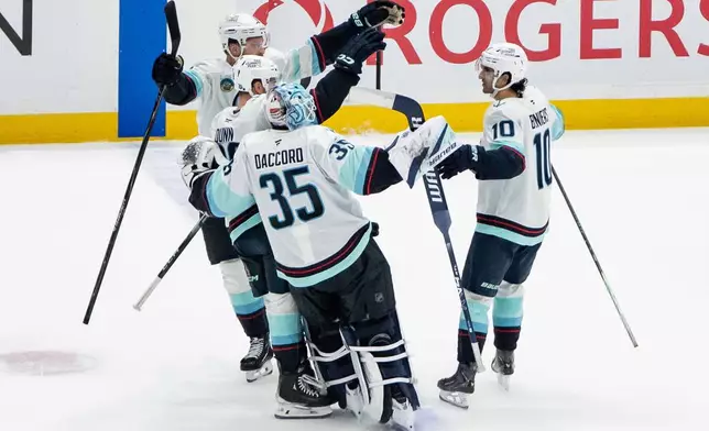 Seattle Kraken's Matty Beniers (10) celebrates his winning goal against the Vancouver Canucks with his teammates in shootout NHL hockey action in Vancouver, Friday, Jan. 2, 2026. (Ethan Cairns/The Canadian Press via AP)