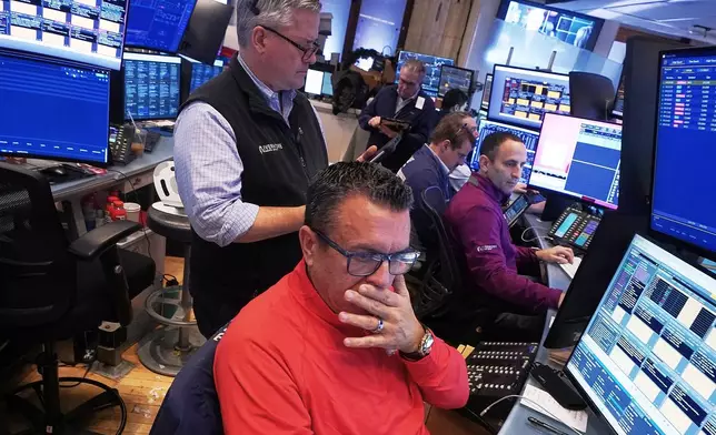 Trader Robert Finnerty Jr., foreground, works with colleagues on the floor of the New York Stock Exchange, Monday, Jan. 12, 2026. (AP Photo/Richard Drew)