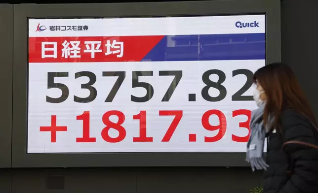A person walks in front of an electronic stock board showing Japan's Nikkei index at a securities firm Tuesday, Jan. 13, 2026, in Tokyo. (Kyodo News via AP)