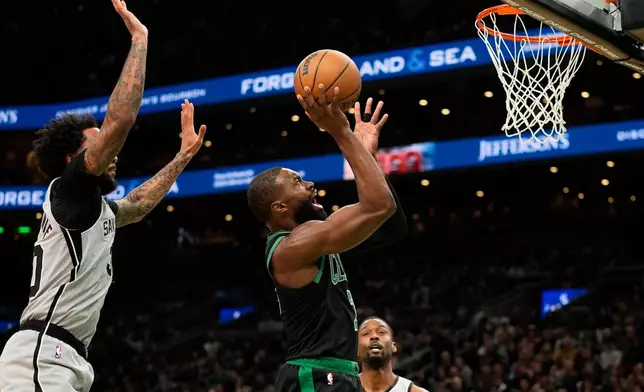 Boston Celtics guard Jaylen Brown (7) shoots while being defended by San Antonio Spurs forward Julian Champagnie (30) during the first half of an NBA basketball game Saturday, Jan. 10, 2026, in Boston. (AP Photo/Robert F. Bukaty)
