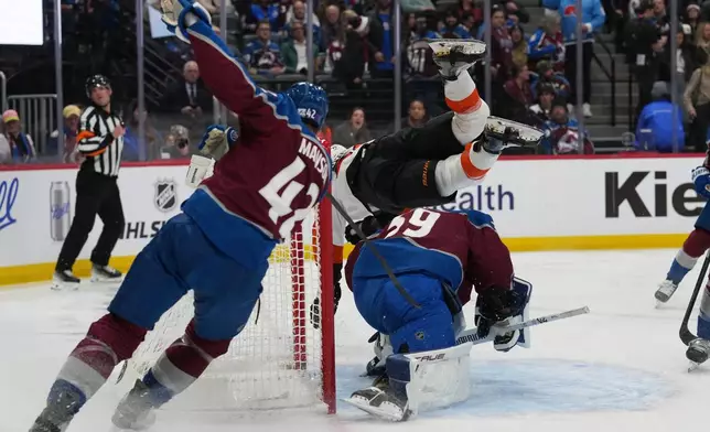 Colorado Avalanche defenseman Josh Manson, left, tries to stop after propelling Philadelphia Flyers center Christian Dvorak, top right, into Avalanche goaltender MacKenzie Blackwood, bottom right, in the second period of an NHL hockey game Friday, Jan. 23, 2026, in Denver. (AP Photo/David Zalubowski)
