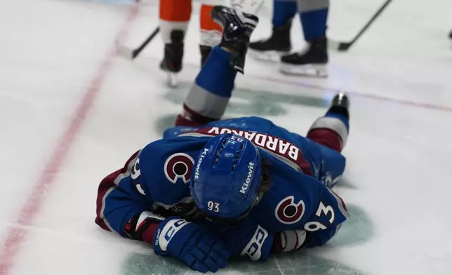 Colorado Avalanche center Zakhar Bardakov lies on the ice after being injured when he ran into the end boards in the third period of an NHL hockey game against the Philadelphia Flyers, Friday, Jan. 23, 2026, in Denver. (AP Photo/David Zalubowski)