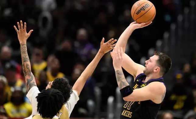 Los Angeles Lakers guard Luka Doncic, right, looks to shoot during the first half of an NBA basketball game against the Washington Wizards, Friday, Jan. 30, 2026, in Washington. (AP Photo/Nick Wass)